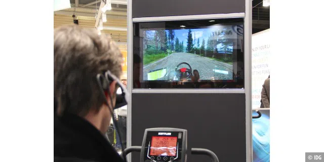 Auch das sind Wearables: ein Heimtraineranbieter zeigt auf der ISPO, wie wir per Datenbrille und Trainingsgerät durch eine Computerspiel–Landschaft fahren können.