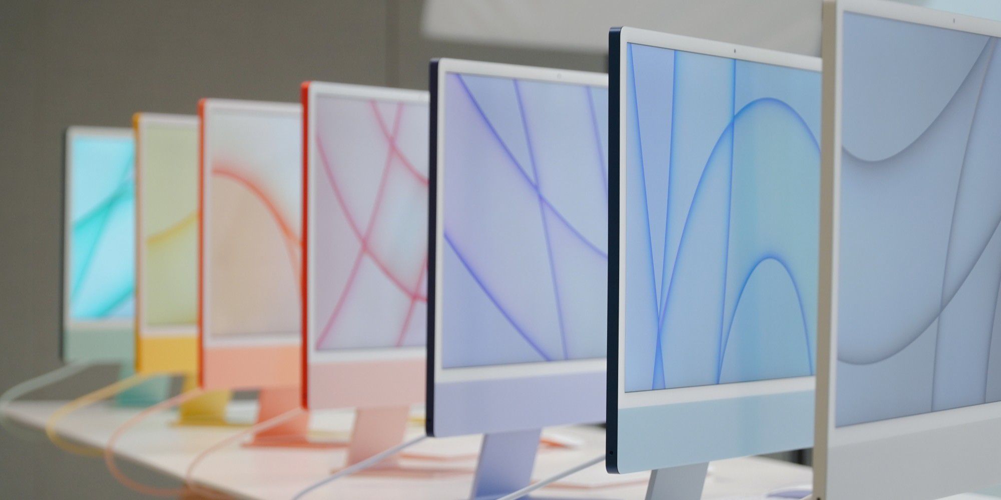 Sieben iMacs von 2021 in verschiedenen Farben hintereinander aufgestellt